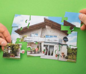 A person holding a puzzle piece with a house on it.