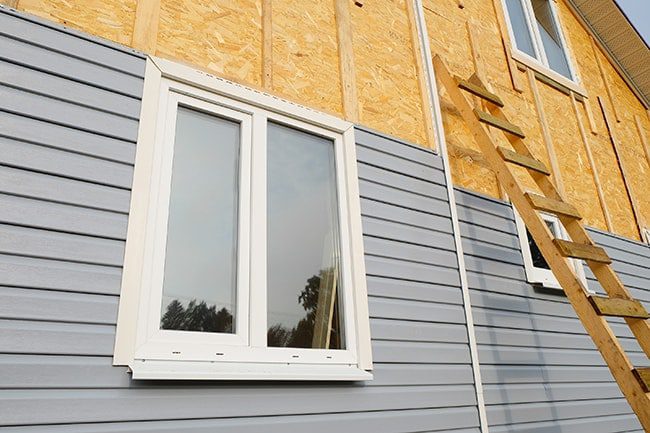 A window in the side of a house with some plywood on it.