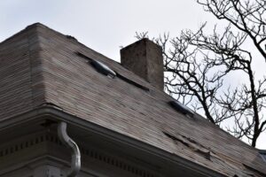 Damaged roof with missing shingles and chimney.